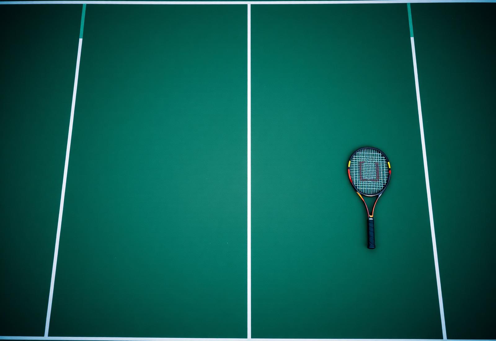 Top-down view of a deep green all-weather tennis court